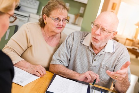 Senior adult couple going over documents in their home with agent at signing