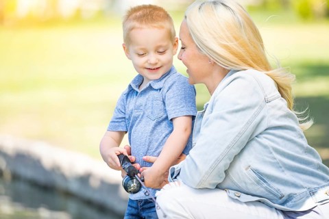 Young caucasian mother and son having fun fishing at the lake
