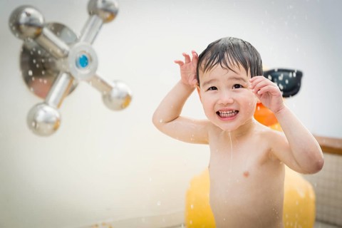 mixed-race boy having fun at the water park with large rubber duck in the background