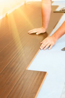 Man installing new laminate wood flooring abstract