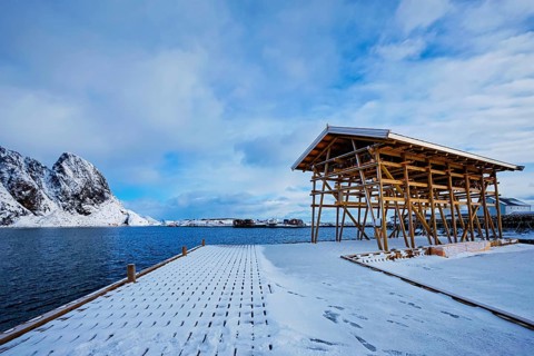 Drying flakes for stockfish cod fish in fjord in winter with snow