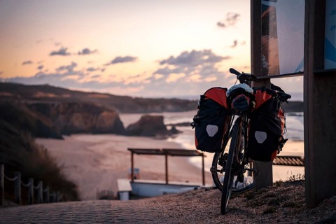 Bicycle with bags by the Almograve beach at sunset
