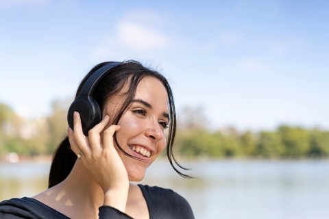 Young woman listening to music outdoors with headphones. Expression of happiness