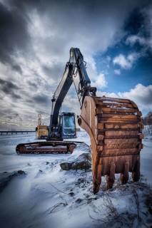 Old excavator with excavator bucket in winter. Road construction in snow. Lofoten islands