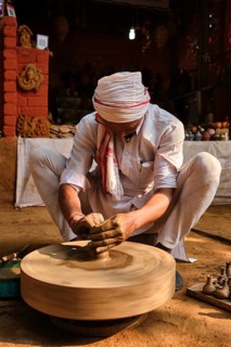 Indian potter at work: throwing the potter's wheel and shaping ceramic vessel and clay ware: pot