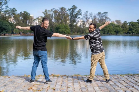 Homosexual mature white male couple holding hands smiling at a lake