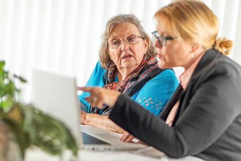 Woman helping senior adult lady on laptop computer