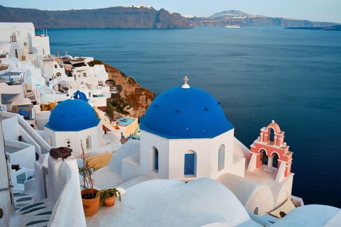 Famous view from viewpoint of Santorini Oia village with blue dome of whitewashed greek orthodox Christian church of traditional greek architecture
