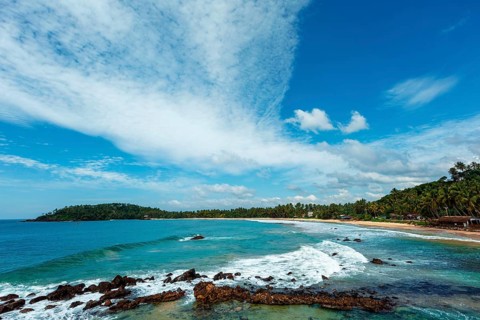 Mirissa beach in Sri Lanka in daytime with clouds and waves in sea