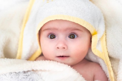 Cute baby girl after bath wrapped in towel. Hygiene and health care concept of new born