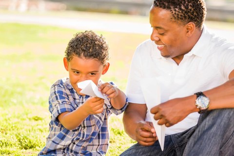 Happy african american father and mixed-race son playing with paper airplanes in the park