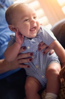 Happy mixed-race couple enjoying their newborn son in the light of the window