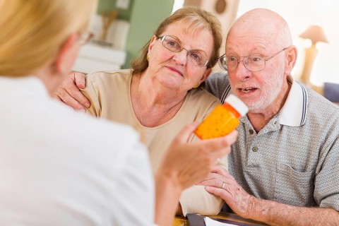 Doctor or nurse explaining prescription medicine to senior adult couple