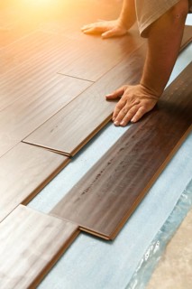 Man installing new laminate wood flooring abstract