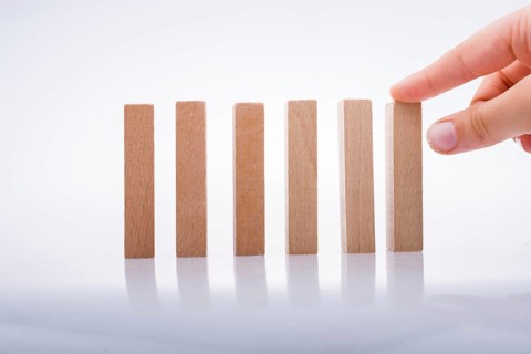 Hand holding wooden domino on a white background