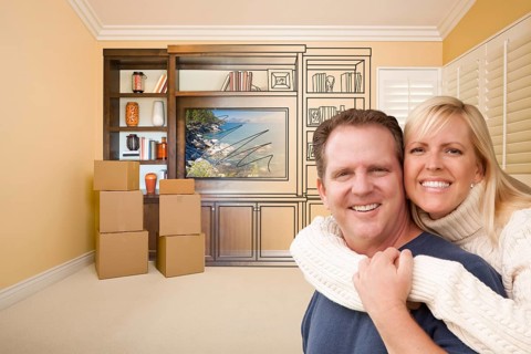 Young couple in room with moving boxes and drawing of entertainment unit on wall
