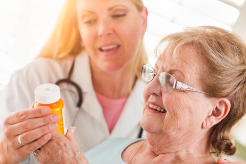 Happy female doctor or nurse explaining prescription to senior adult woman