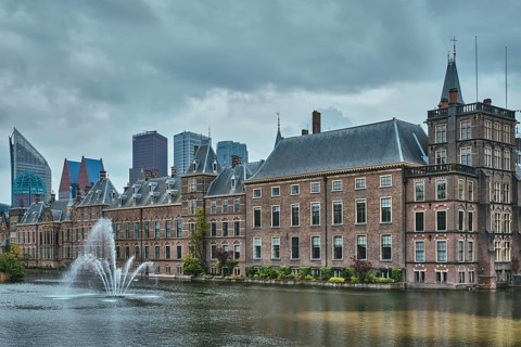 View of the Binnenhof House of Parliament and the Hofvijver lake with downtown skyscrapers in background
