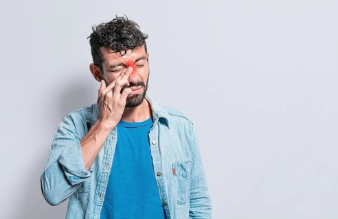 Person with pain touching nose. A person with nasal bridge pain