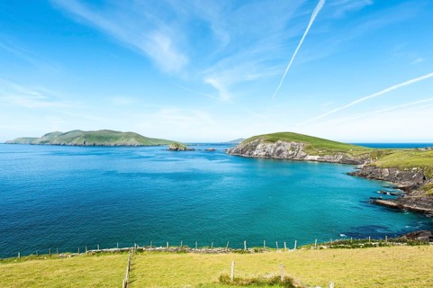 View of green coastal landscape with Blasket Islands behind left
