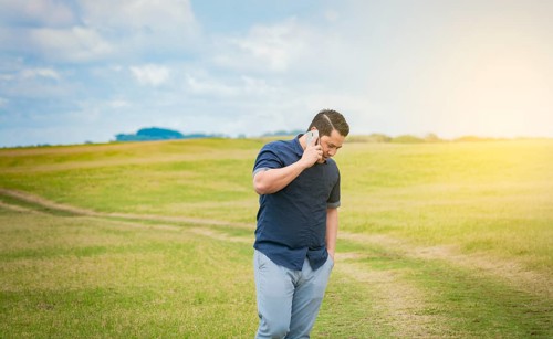 Person with his cell phone in the field talking on the phone