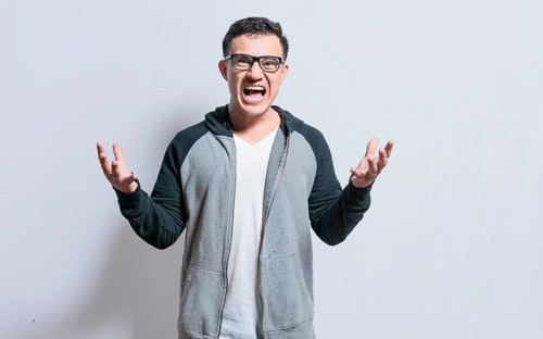 Young man with open hands screaming angry to the camera