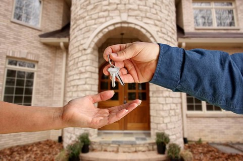 Handing over the house keys in front of a beautiful new home