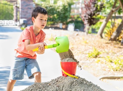 Young caucasian and chinese boy playing with shovel and bucket
