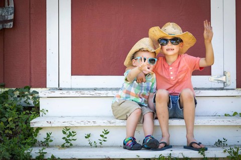 mixed-race chinese and caucasian young brothers having fun wearing sunglasses and cowboy hats