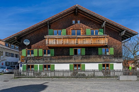 Fassade mit Holzschindeln und gruenen Fensterlaeden