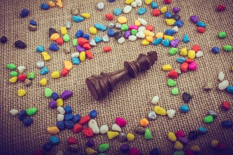 Chess king amid colorful pebbles on canvas background