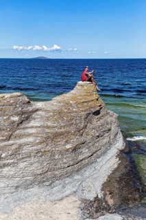 Hiker sitting on limestone pillar photographing landscape