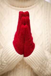 Woman wearing red mittens with hands praying