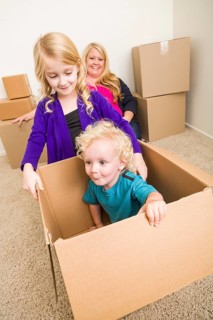 Playful young family in empty room playing with moving boxes