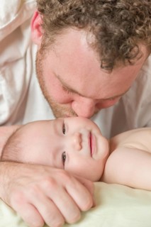 mixed-race chinese and caucasian baby boy laying in bed with his father