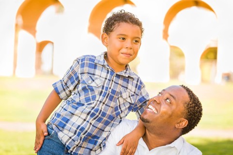 Happy african american father and mixed-race son playing at the park