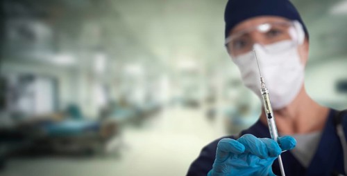 Doctor or nurse holding medical syringe with needle within hospital