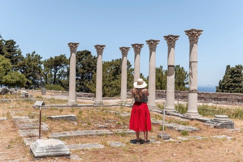 Young woman with dress in front of ruins with columns