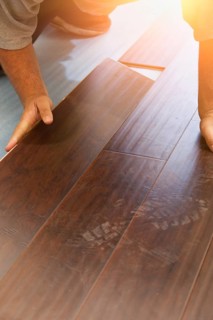 Man installing new laminate wood flooring abstract