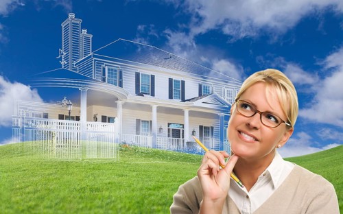 Smiling woman holding pencil looking over to ghosted house drawing