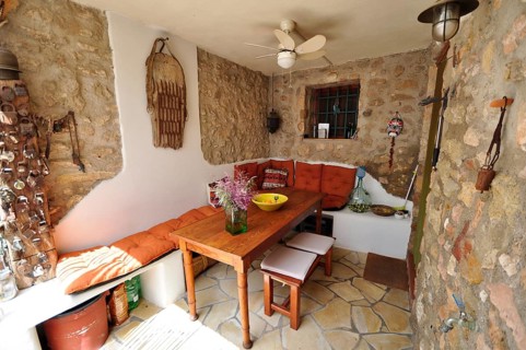 Wooden table with bench in covered dining area with natural stone wall