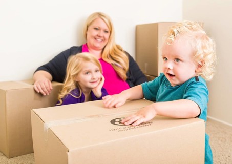 Playful young family in empty room playing with moving boxes