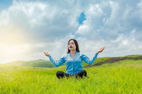 Girl sitting doing meditation yoga in the field