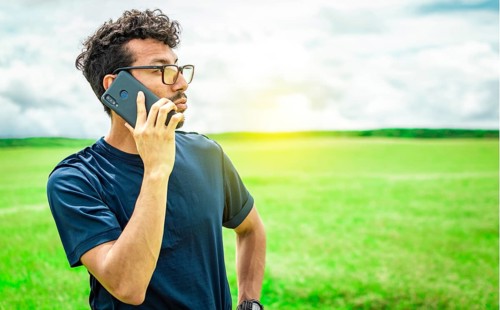 Person with his cell phone in the field calling on the phone