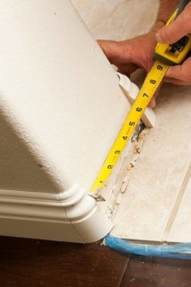 Contractor measuring for new baseboard with bull nose corners and new laminate flooring abstract