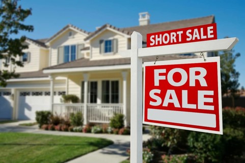 Short sale home for sale real estate sign in front of new house