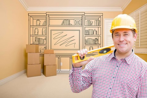 Male construction worker wearing hard hat in room with drawing of entertainment unit on wall