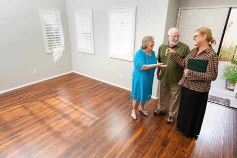 Female real estate agent handing new house keys to senior adult couple in new home