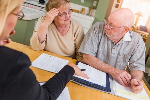 Senior adult couple going over documents in their home with agent at signing