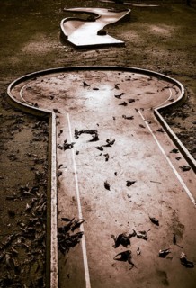 Verlassene Minigolfanlage mit Herbstlaub bedeckt